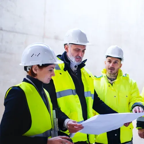 İş güvenliği ekipmanlı üç mühendisin proje planı üzerinde görüşmesi